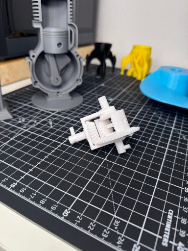 Ein weißes, 3D-gedrucktes Objekt liegt auf einem Schreibtisch mit verschiedenen Werkzeugen.