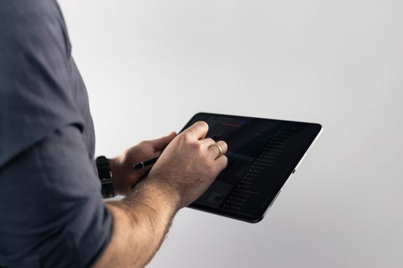Person nutzt ein Tablet und schreibt darauf mit einem Stylus.